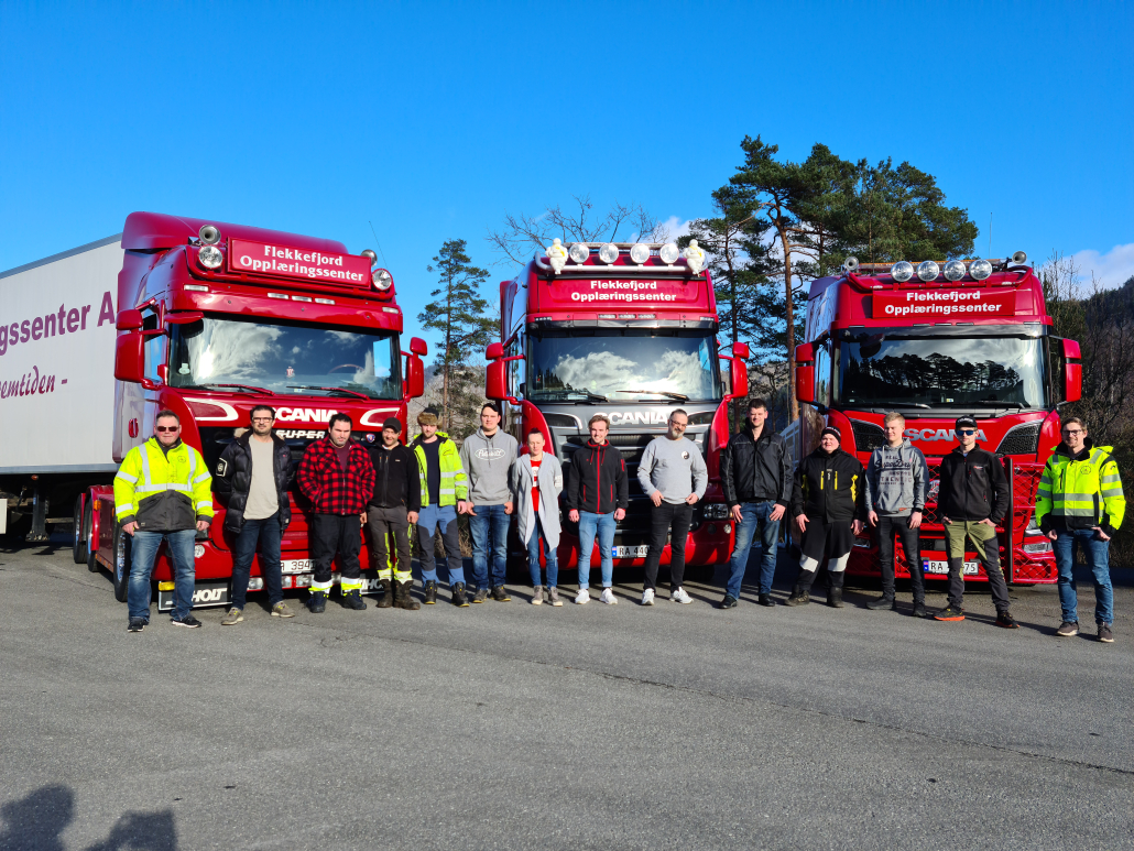 Gruppe kursdeltakere foran tre lastebiler hos Flekkefjord Opplæringssenter